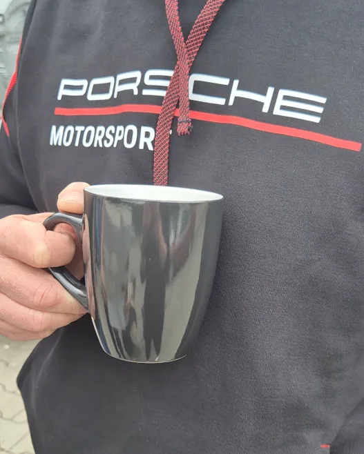 Kaffeetasse vor Porsche Motorsport Pullover